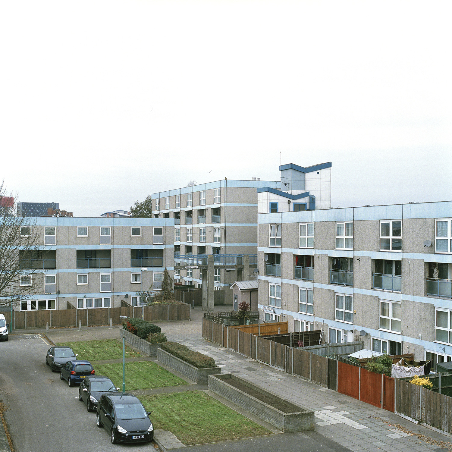 View looking over to three blocks of concrete blocks of flats, with back gardens lines up in a row