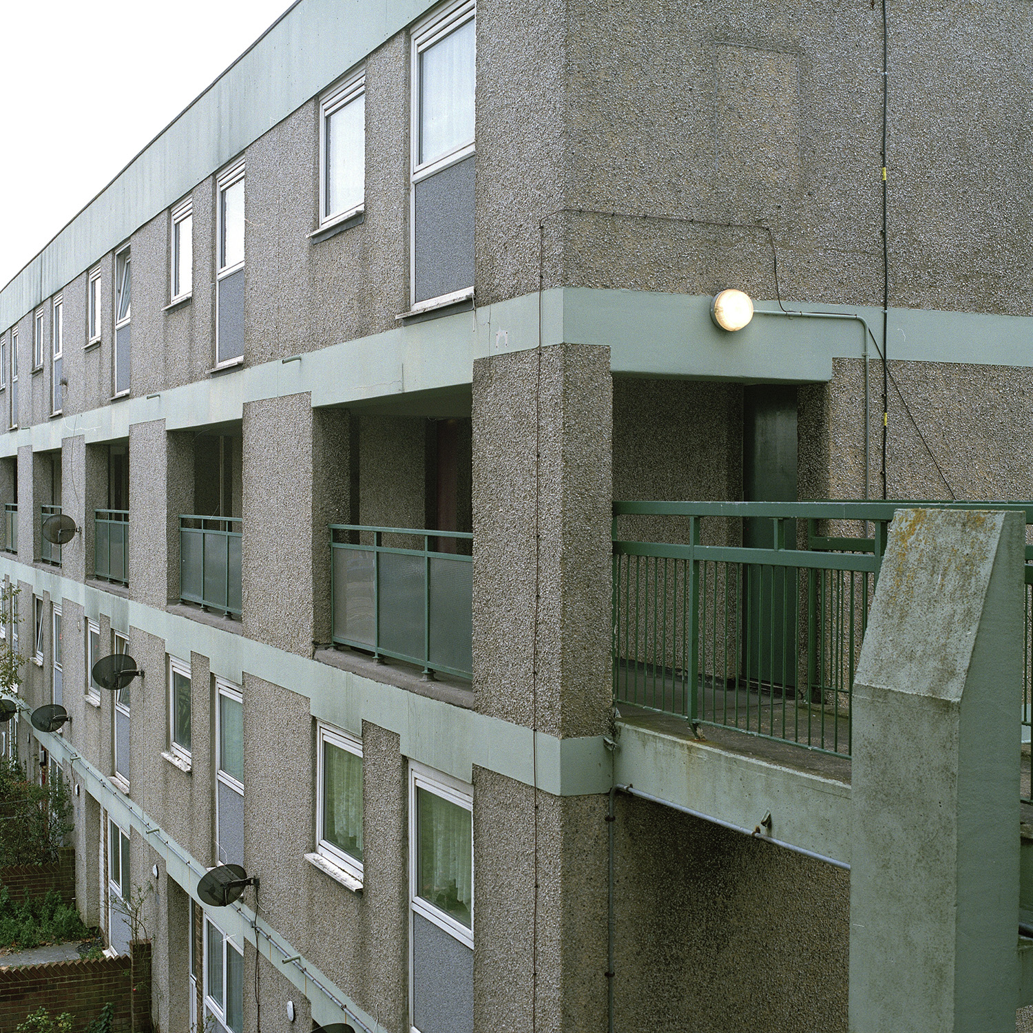 A green elevated walkway dissapears in to a block of flats in Landport