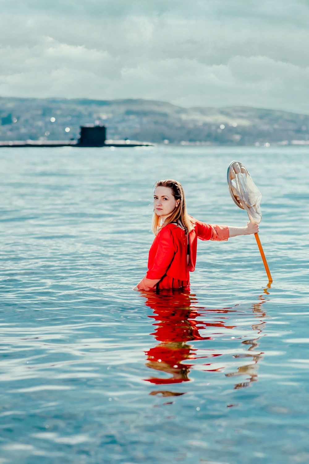 Jenna Watt standing out in the waters of Faslane, with a submarine on the horizon.