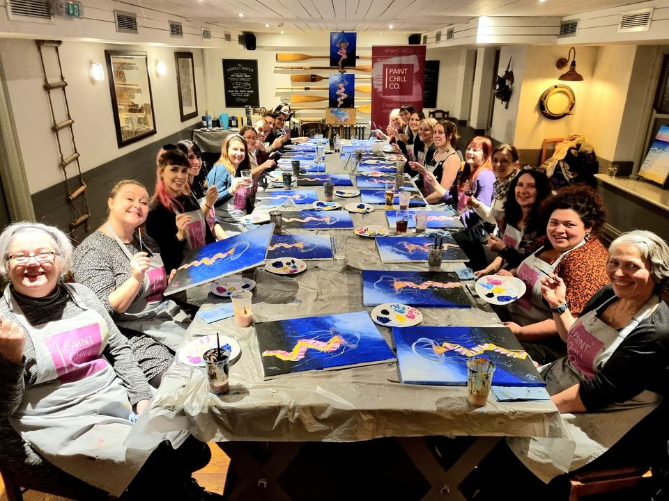 A happy group of painters around a pub table at a Paint 'n' Sip event